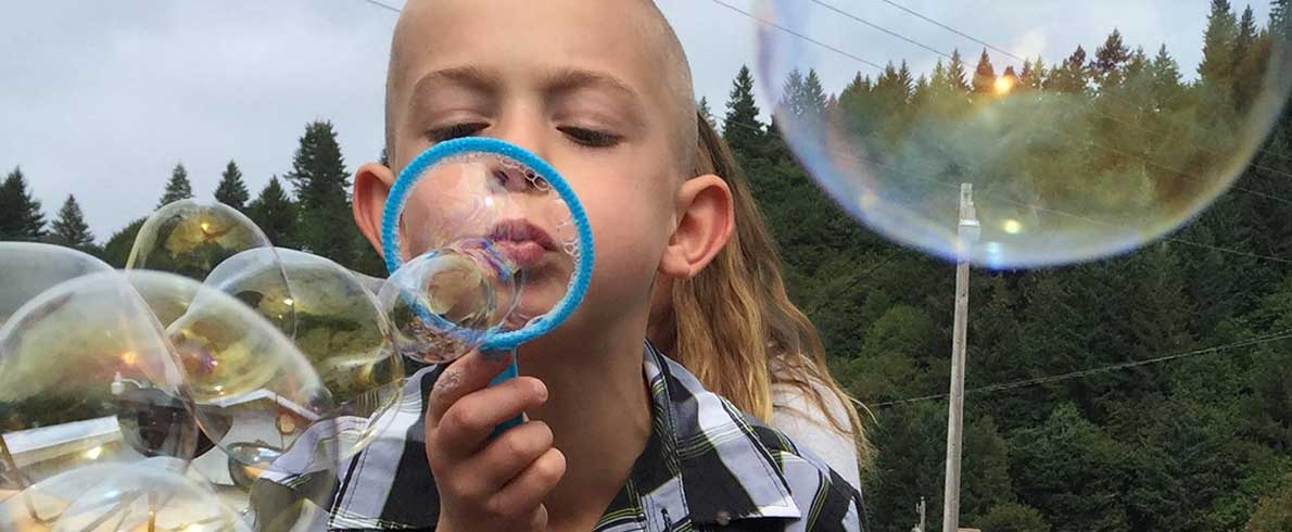 Child blowing bubbles outside